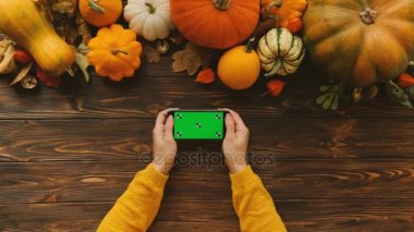 Ahşap masa üstüne kabak ile sonbahar kompozisyon. Yeşil ekran ve ahşap masa üzerinde izleme hareket ile siyah akıllı telefon. Chroma anahtar. Üstten Görünüm