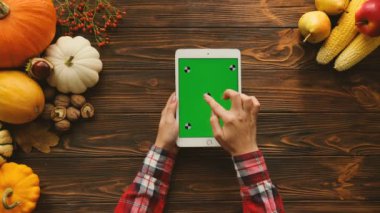 Kabaklar, meyve ve sebze ahşap tablo ile sonbahar kompozisyon. Kaydırma, dokunarak ve yeşil ekran beyaz tablet cihaz üzerindeki Sayfa yakınlaştırma kadın. Üstten Görünüm. Chroma anahtar. Hareket izleme