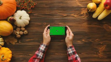 Kaydırma ve siyah smartphone ile yatay pozisyonda yeşil ekran sayfalarında swiping parmaklar. Tablo yukarıdan Sonbahar meyve ve sebze ile. Chroma anahtar. Hareket izleme