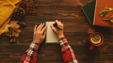 Sonbahar tablosu üstten görünüm kompozisyon. Kadın not defterinde ahşap masanın üzerine yazma. İyi günler. Kitaplar, akçaağaç kahverengi ahşap masa üzerinde bırakır..