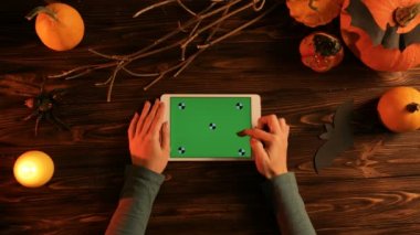 Kabakları ile ahşap masa üstünde yeşil perde ile beyaz tablet bilgisayarda dokunarak kadın yarasalar, mum içinde belgili tanımlık karanlık. Cadılar Bayramı düz yatıyordu. Üstten Görünüm. Chroma anahtar. Hareket izleme