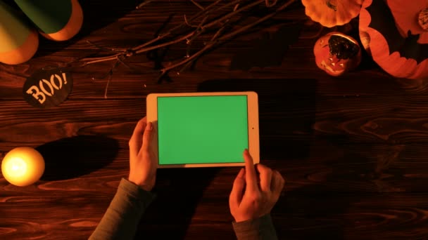Vista superior de Halloween con calabazas, velas, murciélagos y tableta blanca con pantalla verde en la mesa de madera. Mujer desplazándose, tocando en la pantalla táctil del pad. Clave de croma — Vídeos de Stock