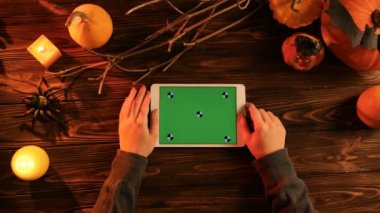 Swiping, beyaz tablet cihaz sayfalarında eski ahşap masa üstünde yeşil perde ile kaydırma kadın. Cadılar Bayramı üstten görünüm. Hareket izleme. Chroma anahtar