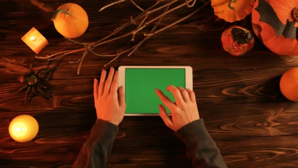Halloween top view concept, Femme utilisant un ordinateur tablette blanche avec écran vert sur la table en bois. Couché plat avec décor d'Halloween. Citrouilles avec des bougies dans le noir. Clé chromatique — Video