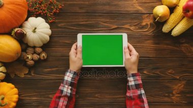 Sonbahar meyve ve sebze ile ahşap masa üzerinde yatay konumda yeşil ekran beyaz tablet bilgisayar. Üstten Görünüm. Sayfa kaydırma parmak. Sonbahar. Chroma anahtar