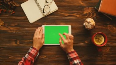 Sonbahar konsepti düz yatıyordu. Ahşap masa üzerinde yatay konumda yeşil ekranlı tablet aygıtı kullanan kadın. Üstten Görünüm. Chroma anahtar