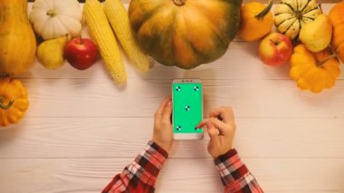 Beyaz ahşap masa üzerinde üstten görünüm sebze, meyve ve yeşil ekranlı akıllı telefon. Düz yatıyordu. Chroma anahtar. Kaydırma, yakınlaştırma.