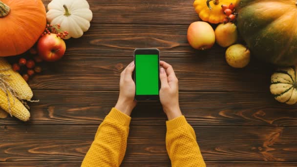 लकड़ी की मेज पर ग्रीन स्क्रीन और शरद ऋतु के फलों और सब्जियों के साथ स्मार्टफोन। शीर्ष दृश्य शॉट। क्रोमा कुंजी — स्टॉक वीडियो