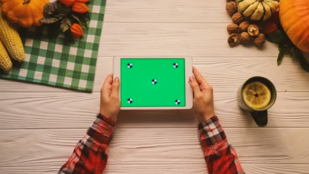 Autumn flat lay with fruits, nuts and vegetables on the white wooden table. Woman scrolling, tapping, zooming pages on tablet device with green screen. Horizontal position. Chroma key. Tracking motion — Stock Video