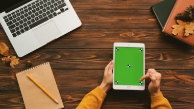 Dizüstü bilgisayar ve dizüstü bilgisayarlar ile ahşap masa üzerinde beyaz tablet bilgisayar kullanan kadın en iyi görünümü. Hareket izleme. Yeşil ekran. Chroma anahtar.