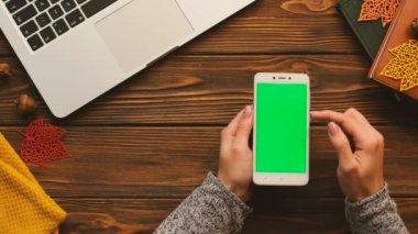 Sonbahar üstten görünüm. Dokunarak, yeşil ekran sayfaları smartphone üzerinde yakınlaştırma kadın. Ahşap Resepsiyon arka plan. Chroma anahtar. Dikey