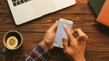 New York - 10 Eylül 2017: Uber app üzerinde beyaz smartphone kullanan adam. Sipariş bir araba, taksi, taksi ve hedef seçme adam. Ahşap masa arka plan üzerinde atış Üstten Görünüm