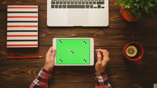 Tableta blanca con pantalla verde en la mesa de madera con elementos rojos. Acostado. Vista superior. Clave de croma. Movimiento de seguimiento — Vídeos de Stock