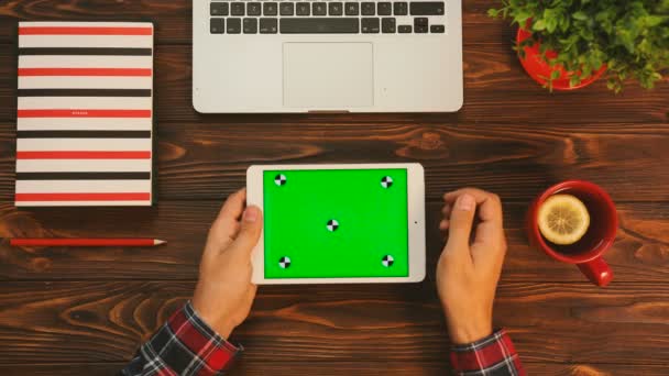 Hombre trabajando en la tableta blanca con pantalla verde. Movimiento de rastreo. Clave de croma. Vista superior de la mesa con elementos rojos — Vídeos de Stock