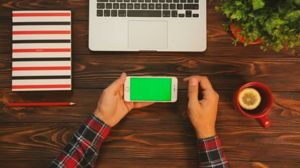 男性的手指缩放、 绿色的智能手机屏幕上攻丝。表顶视图与红色的项目上的木制的背景。色度键 — 图库视频影像