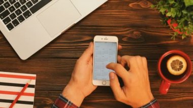 New York - 10 Eylül 2017: Takvim uygulaması üzerinde beyaz bir akıllı telefon kullanan adam. Gelecek için plan yapıyor adam yeni bir olay yapma. Fincan çay, defter ve laptop ile eski ahşap masa üzerinde Üstten Görünüm