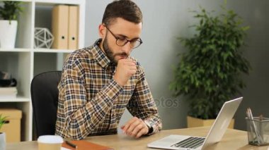 İyi ve öksürük duygu değil güneşli bir günde, modern ofisinde masa üzerinde dizüstü bilgisayar kullanarak başarılı genç iş adamı. Kapalı.