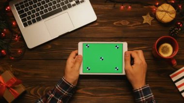 Tablo yukarıdan dokunarak, kaydırma, sayfalar beyaz tablet ile yeşil perde üzerinde yakınlaştırma erkek el. Noel dekor, çay bardağı, tanımlama bilgileri, garland. Chroma anahtar. Hareket izleme