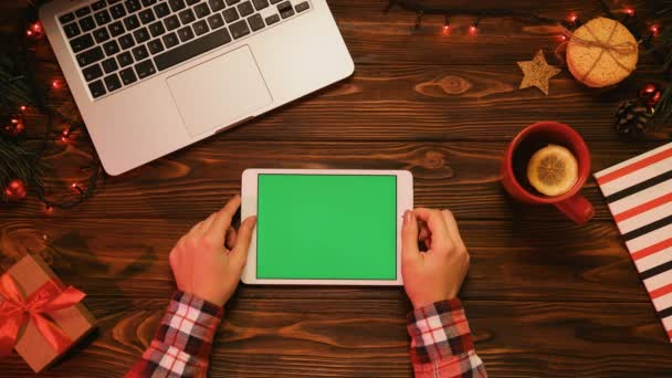 Yukarıdan görüntüleyin. Noel dekor ahşap masa. Yeşil ekran beyaz tablet bilgisayar. Kadın kaydırma sayfaları. Chroma anahtar — Stok video
