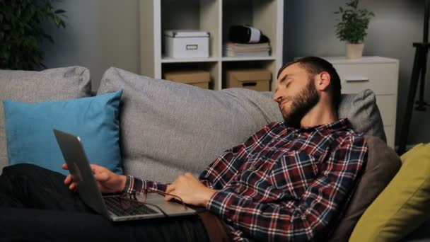 ひげを持つ若い白人男はソファに横になっている、勤勉な一日の後に眠っています。室内撮影. — ストック動画