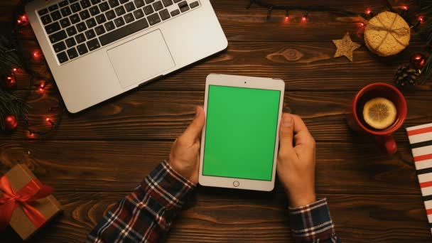 L'uomo scorre le pagine sul touchscreen del tablet. Schermo verde. Chiave cromatica. Concetto di Natale vista dall'alto . — Video Stock