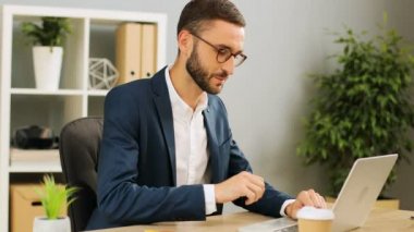 Ciddi beyaz iş adamı, Ofis Masası, kayıt duygu mutlu ve iddialı meslektaşları ile bir dizüstü bilgisayar kullanarak. Kapalı atış. Yakın çekim.