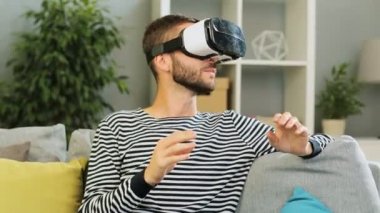 Beyaz adam bir oturma odası arka plan gri arka plan video izlemek için bir kulaklık takıyor. Kapalı.