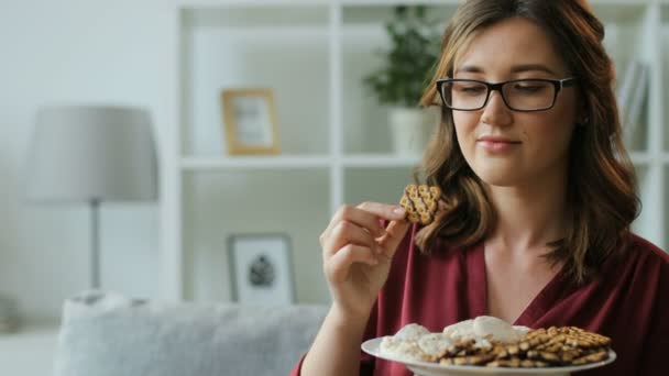 Жінка в окулярах їсть печиво — стокове відео