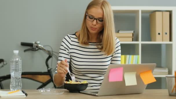 Zakenvrouw eten in de buurt van computer — Stockvideo