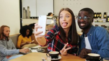 Mutlu arkadaş smartphone, kahve dükkanı arka plan selfie çekerken komik surat. Kapalı.