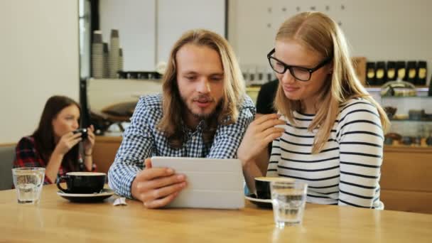 Щаслива молода пара тримає цифровий планшетний комп'ютер і дивиться на нього в кав'ярні, відчуває себе щасливим і задоволеним. Крупним планом постріл . — стокове відео
