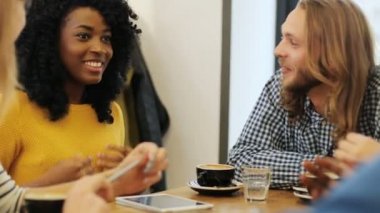 Neşeli ve çekici grup arkadaşıyla birlikte sohbet ve birlikte küçük bir kafede kahve yudumlarken gülüyor. Yakın çekim.