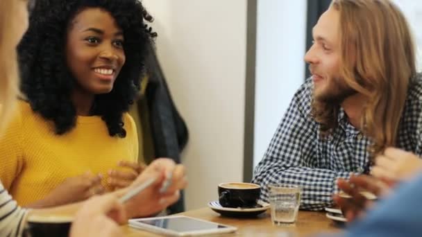 Grupo alegre e atraente de amigos conversando e rindo juntos em um pequeno café, enquanto bebem café. Fechar . — Vídeo de Stock