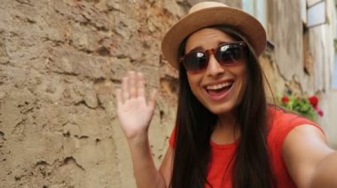 Görüntülü sohbet açık havada eski şehrin sokak sahip genç çekici turist kadın. Sallayarak ve kameraya gülümseyen kadın. yakın çekim