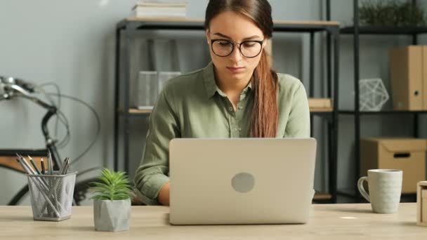 Młody atrakcyjny brunetka kobieta pracę z laptopem w nowoczesny Urząd Miejski. Kobieta, wpisując na klawiaturze, czytanie, surfing inernet. Z bliska — Wideo stockowe