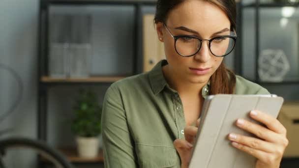 Giovane donna d'affari in occhiali utilizzando tablet touchscreen nel moderno ufficio urbano e sorridente. vicino — Video Stock