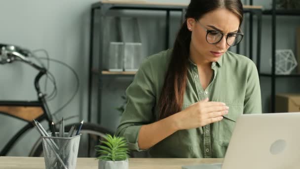 Atractiva mujer de negocios que sufre de dolor de corazón mientras trabaja con el ordenador portátil en la oficina urbana moderna. Mujer con arritmia — Vídeos de Stock