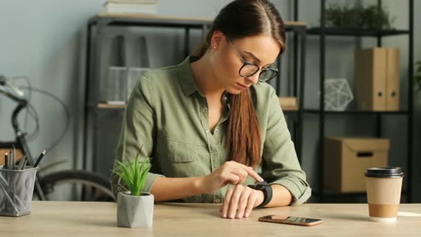 Wanita berambut coklat cantik menggunakan jam tangan pintar dengan layar sentuh di kantor perkotaan modern. Wanita mengetuk di layar sentuh. Tutup. — Stok Video