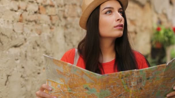 Νέα ελκυστική γυναίκα αναζήτηση ενδιαφέροντα σημεία και δρόμους σε ταξιδιωτικό χάρτη χαρτί και να χαμογελά στη φωτογραφική μηχανή. Κατακόρυφος βολή — Αρχείο Βίντεο
