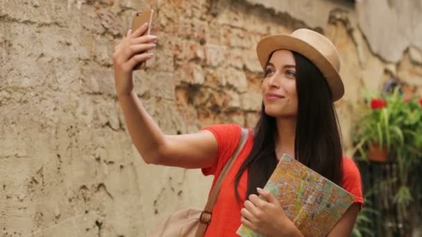 Sorrindo turista feminino tirar selfies enquanto passeia nas ruas da cidade velha. Mulher sorrindo para a câmera e tirando fotos. Fechar — Vídeo de Stock