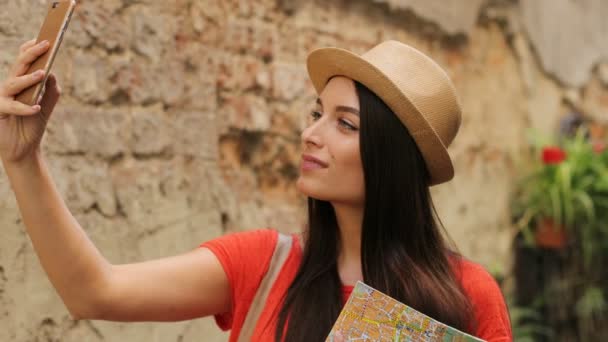 Mujer atractiva joven tomando selfies en el teléfono inteligente mientras viaja por la ciudad vieja. De cerca. — Vídeos de Stock