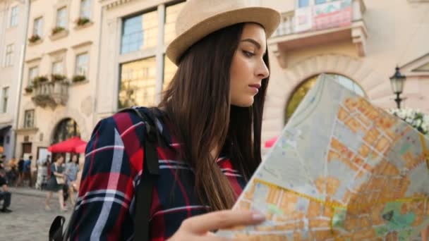 Mulher branca bonita nova com mapa turístico olhando ao redor da rua da cidade. Mulher perdida e a tentar encontrar a rua certa. Fechar — Vídeo de Stock