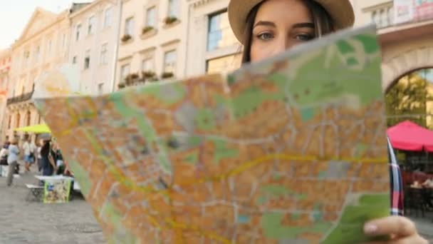 Hermosa mujer joven en sombrero mirando en el mapa turístico para encontrar la calle derecha. Chica turística que busca en la calle con mapa. Mujer viajando. de cerca — Vídeos de Stock