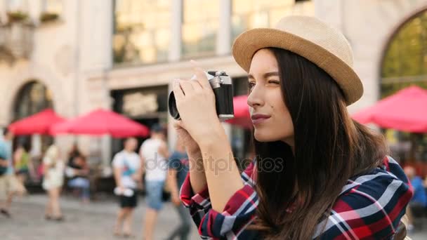 Mujer turista atractiva joven tomando fotos en su vieja cámara vintage mientras camina por las calles de la ciudad vieja. De cerca. — Vídeo de stock