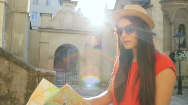 Молодая кавказская женщина с туристической картой, исследующая красивый старый город. Женщина путешествует. Солнечные лучи. Закрыть — стоковое видео