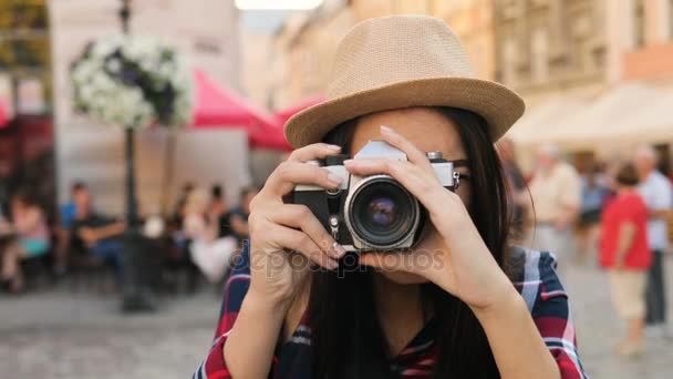 Retrato tiro de mulher sorridente atraente em chapéu tirando fotos em sua antiga câmera vintage. Ao ar livre. Fechar — Vídeo de Stock