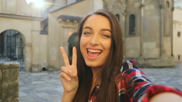 Attractive tourist woman taking funny selfies outdoors in the city street. Girl smiling. Woman traveling and taking photos. close up — Stock Video
