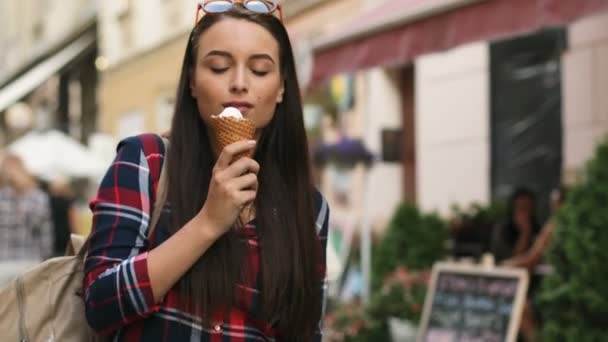 Atractiva turista mujer comiendo helado y mirando a su alrededor mientras camina por la hermosa calle vieja . — Vídeos de Stock