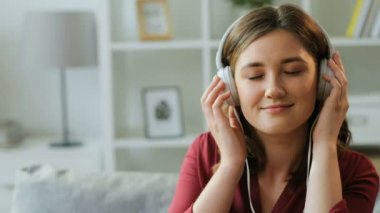 Büyük beyaz kulaklık müzik ve ritim onun oturma odasında kafa hareketli güzel kadın portresi.