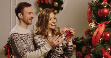 Rahat oturma odasında baubles ile Noel ağacı süsleme ve sarılma genç mutlu bir aile. Noel için hazırlanıyor. Yakın çekim. Portre